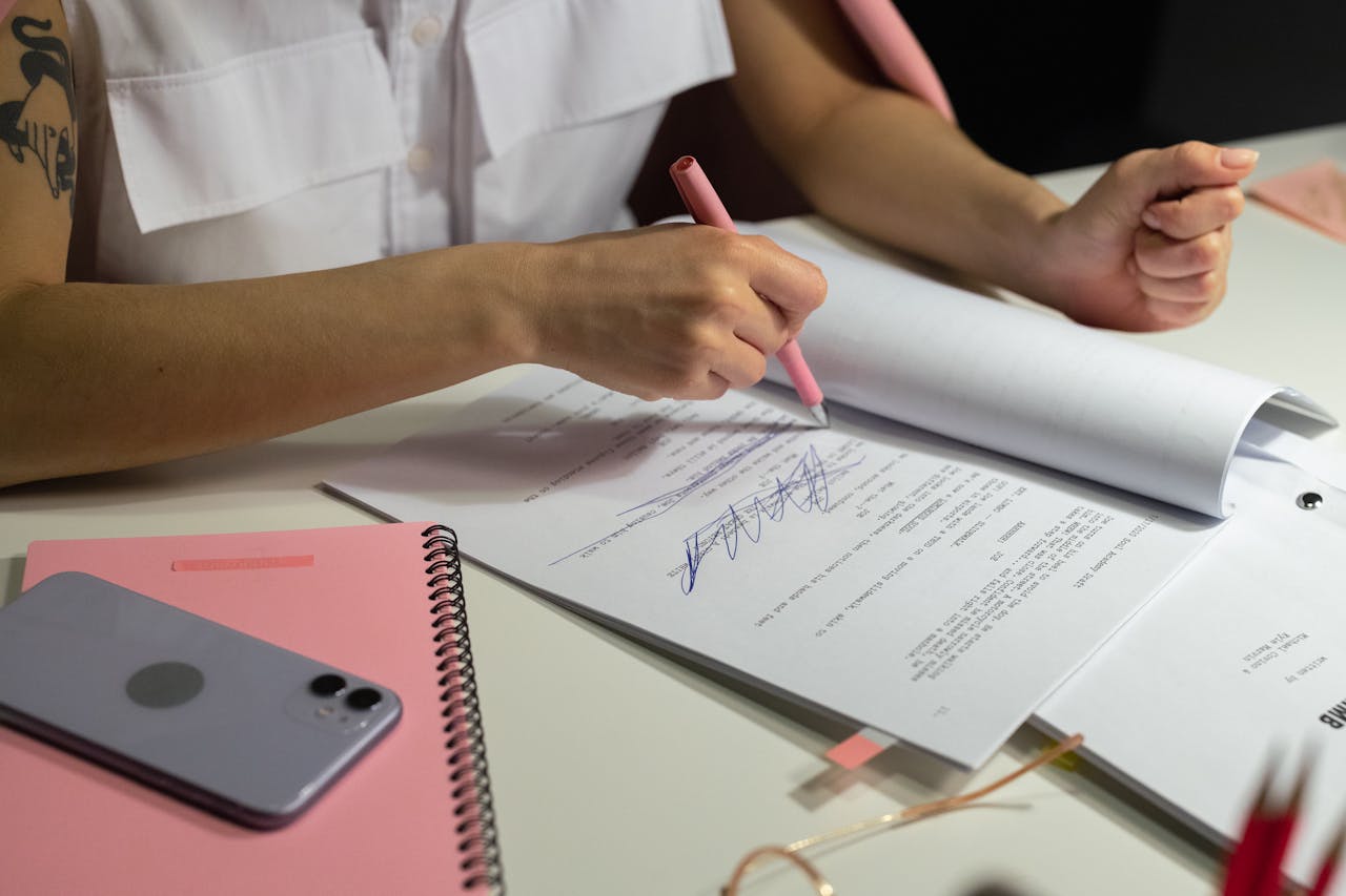gallery-01 Close-up of a person writing on documents at a well-organized office desk.